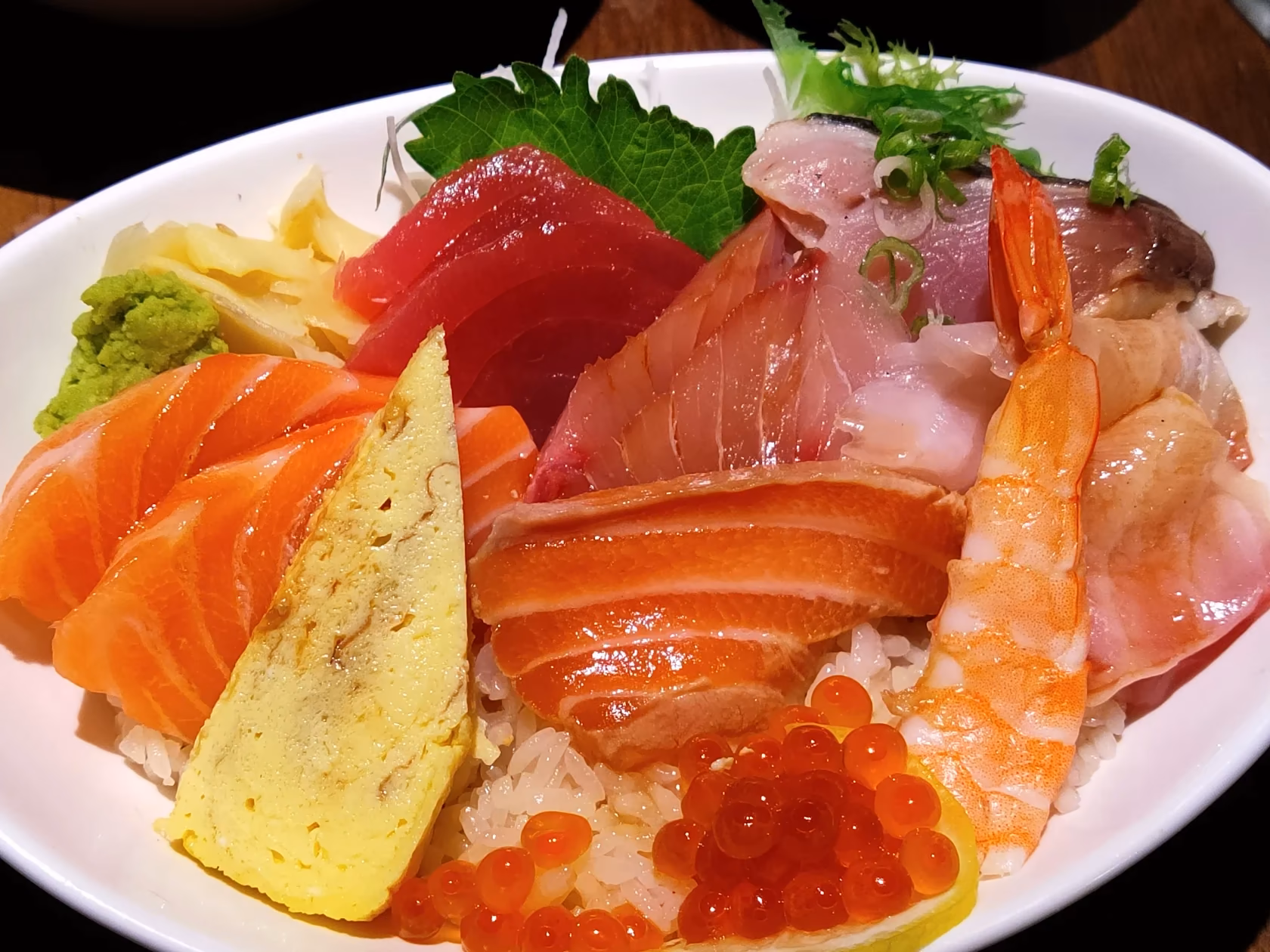 A bowl of chirashi piled with salmon, tuna, shrimp, ikura and tamago